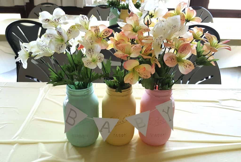 pastel painted mason jars with fake flowers as a baby shower centerpiece