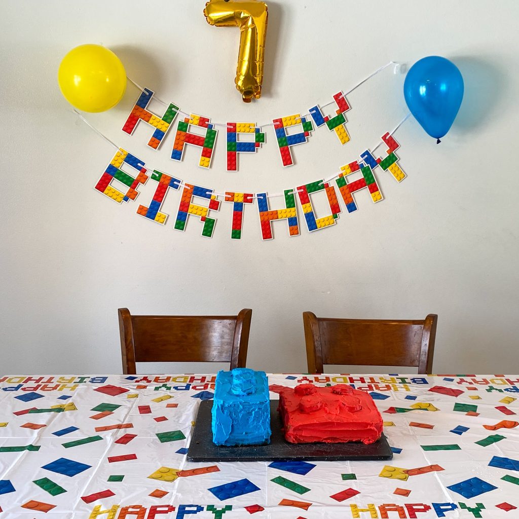 Lego birthday party decorations including tablecloth and "Happy Birthday" banner