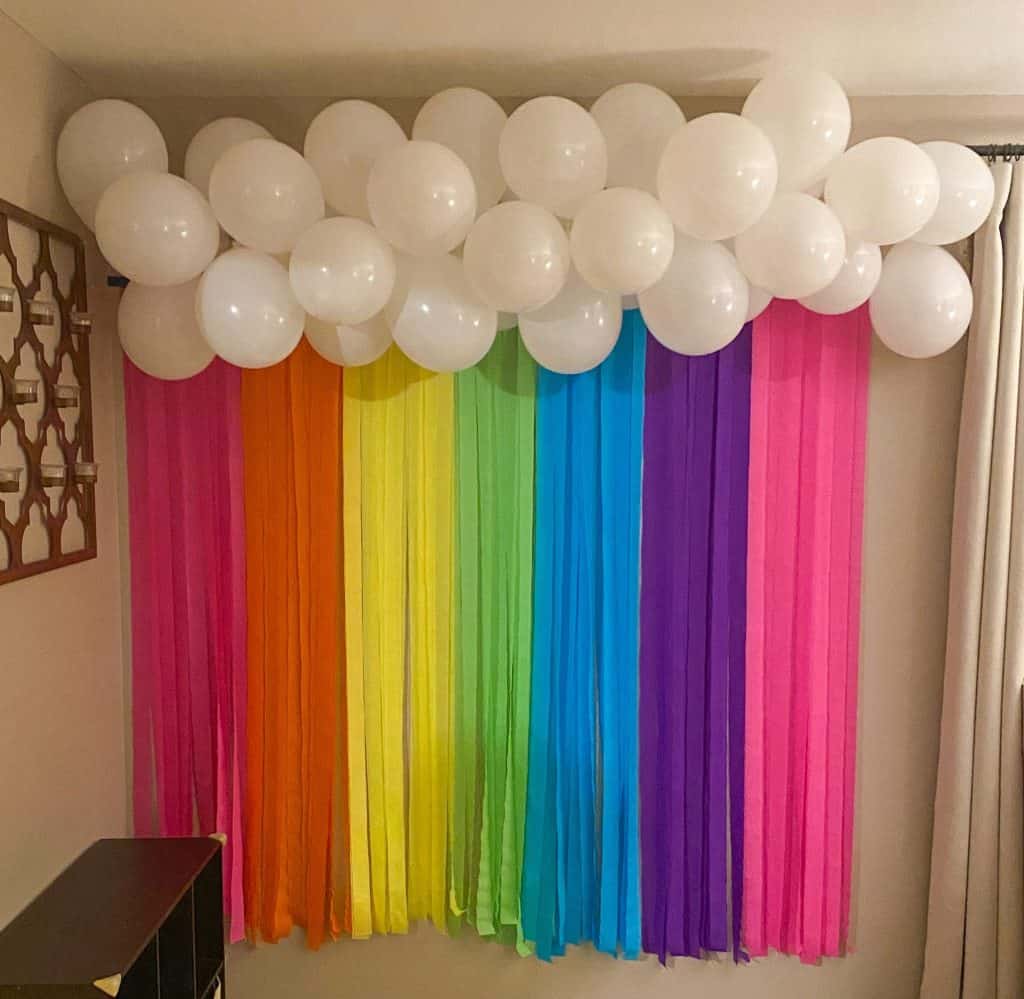 rainbow backdrop of white cloud balloons and colored crepe paper ribbons