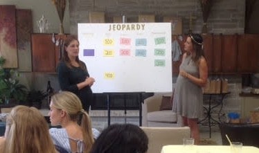 two women standing next to Jeopardy board