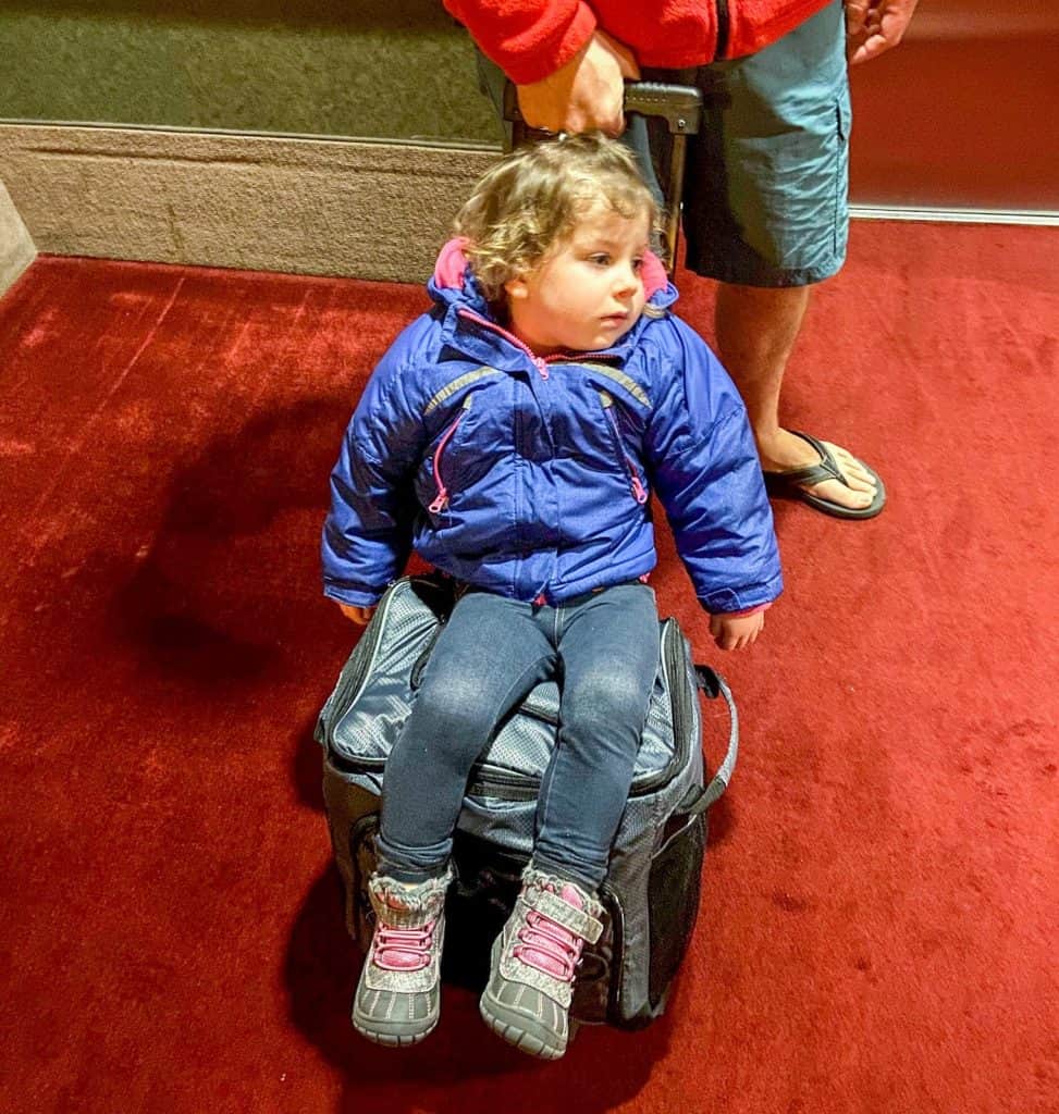 exhausted toddler sitting on luggage